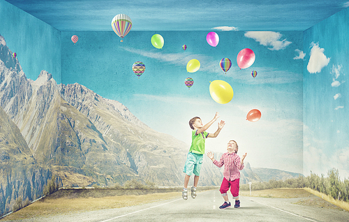 Little cute boys playing joyfully with colorful balloon