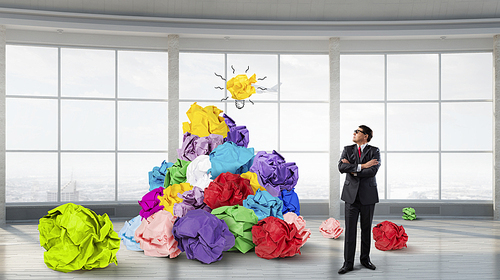 Adult businessman in modern interior and heap of paper balls