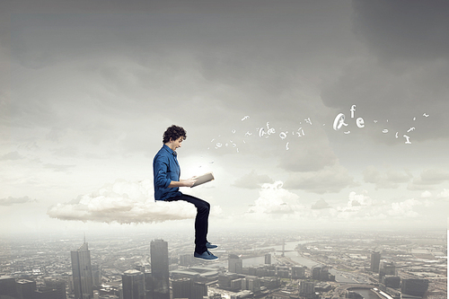 Young handsome man sitting on cloud and reading book