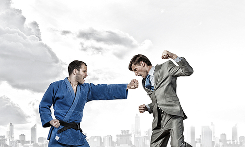 Young determined karate man fighting with businessman in suit