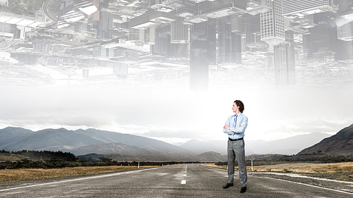 Self assured businessman standing on road with arms crossed on chest
