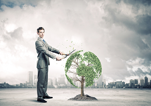 Young businessman cutting tree with scissors in shape of Earth planet