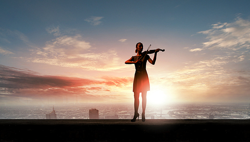 Silhouette of woman playing violin at sunrise