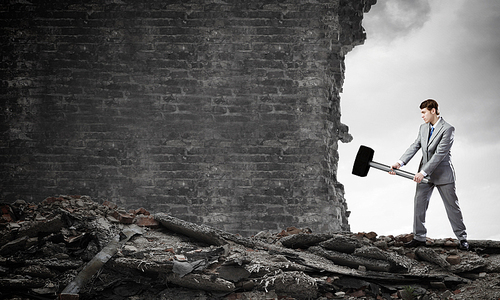 Young businessman breaking old wall with hammer