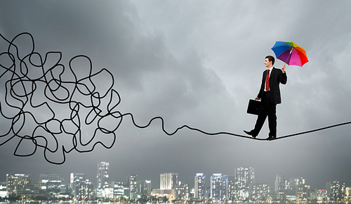 Businessman walking on twisted rope high in sky