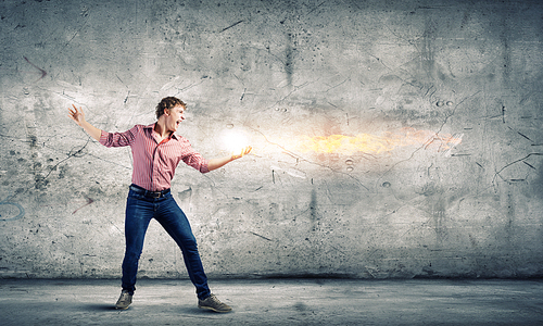 Young man in casual throwing magic fire balls