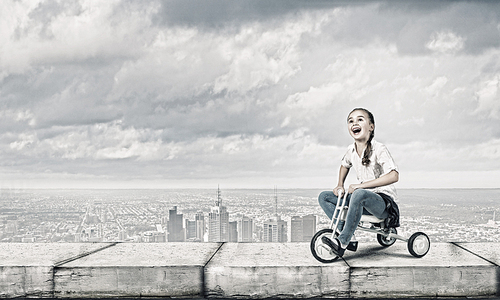 Little cute girl of preschool age riding tricycle