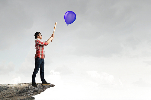 Young hipster guy with bat on hill top