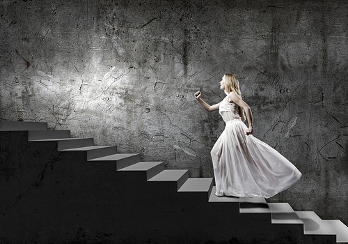 Young woman in white long dress stepping up the staircase