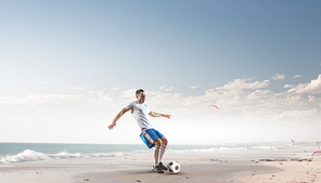 Football player with ball in action at ocean coast