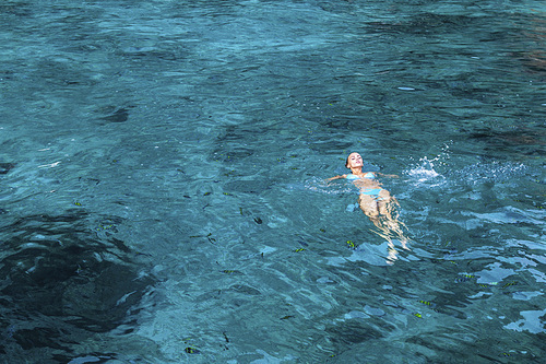 Woman floating on water of Andaman sea, Thailand, plenty of fish around
