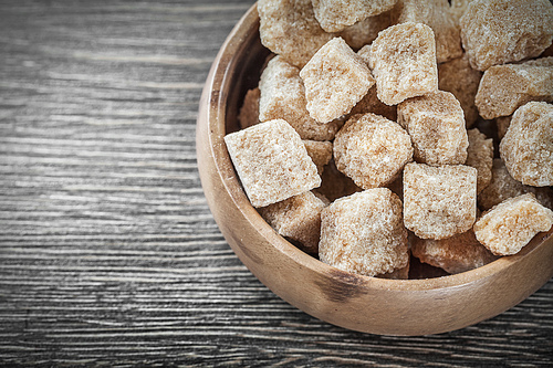 Sugar cubes in bowl on vintage wood board.