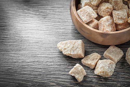 Brown sugar cubes in bowl on vintage wood board.