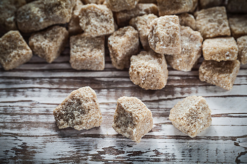 Heap of vintage cane sugar cubes on wooden board.