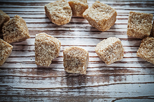 Vintage cane sugar cubes on wooden board top view.