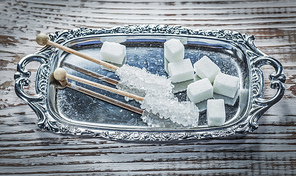 White sugar cubes sticks tray on vintage wooden board.