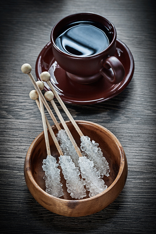 Cup of coffee saucer bowl sugar sticks on wooden board.