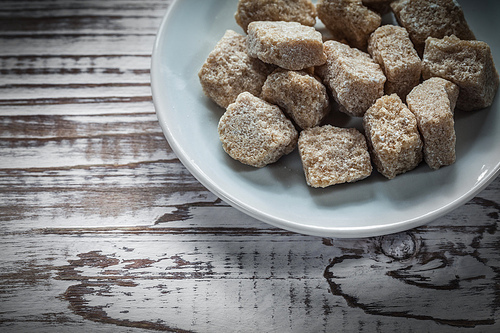 Vintage sugar cubes plate on wooden board.