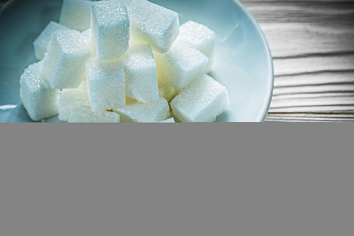 Coffee saucer white sugar cubes on vintage wooden board.