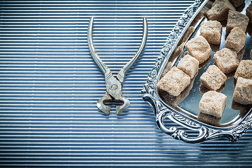 Brown sugar pliers tray on striped background.