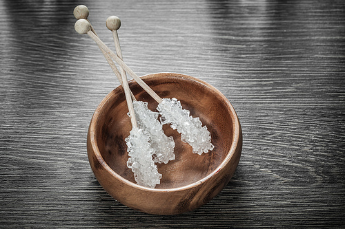 White sugar sticks in wooden bowl.