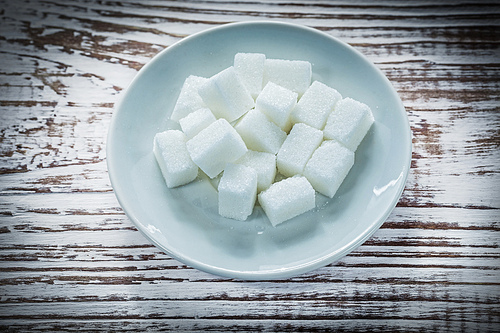 Sugar cubes plate on vintage wooden board.