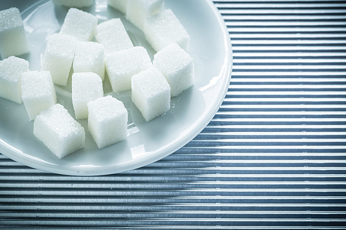 Saucer with sugar cubes on striped background.