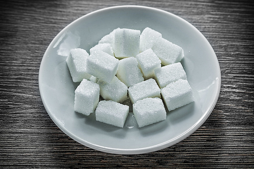 Sugar cubes plate on wooden board.