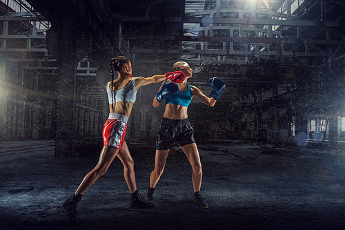 Two young pretty women boxing in desolate building. Mixed media