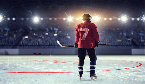 Hockey player in red uniform on ice rink in spotlight