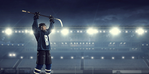 Hockey player in blue uniform on ice rink in spotlight