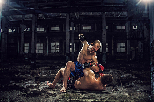 Strong boxers fighting in dark industrial interior mixed media