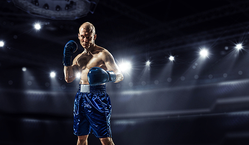 Professional boxer fighting on arena in spotlights mixed media