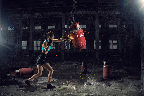 Young pretty woman boxing in desolate building. Mixed media
