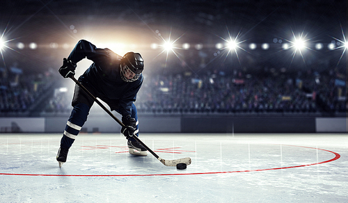 Hockey player in blue uniform on ice rink in spotlight