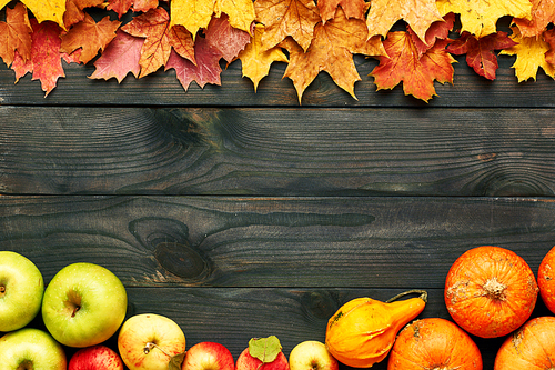 Autumn leaves, apples and pumpkins over old wooden background with copy space