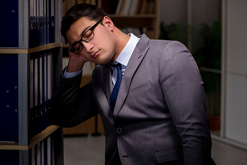 Businessman almost falling asleep working late hours in the office