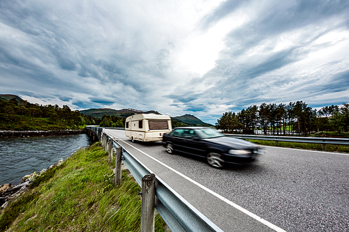 Family vacation travel, holiday trip in motorhome, Caravan car Vacation. Caravan car travels on the highway in Norway. Warning - authentic shooting there is a motion blur.