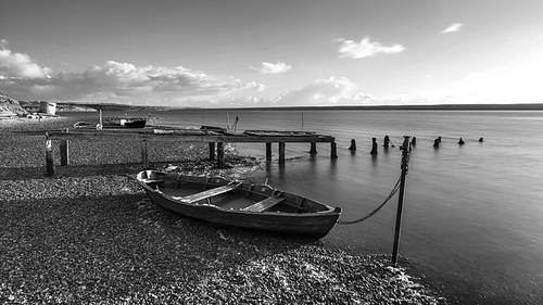 Beautiful black and white sunset landscape image of boats moored in Fleet Lagoon in Dorset England
