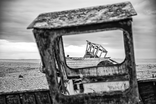 Abandoned derelict fishing boats on shingle beach landscape in Winter