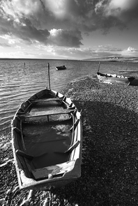 Beautiful black and white sunset landscape image of boats moored in Fleet Lagoon in Dorset England