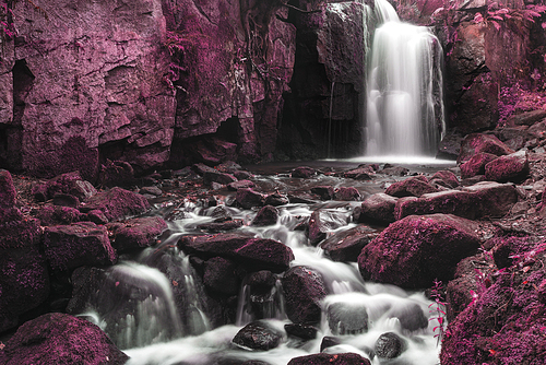 Waterfall in surreal forest landscape long exposure flowing through trees and over rocks