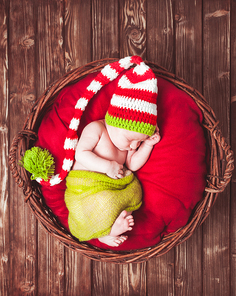 Sleeping newborn baby in hat, on red blanket in basket