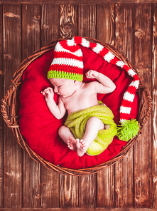 Newborn baby in hat, on red blanket in basket