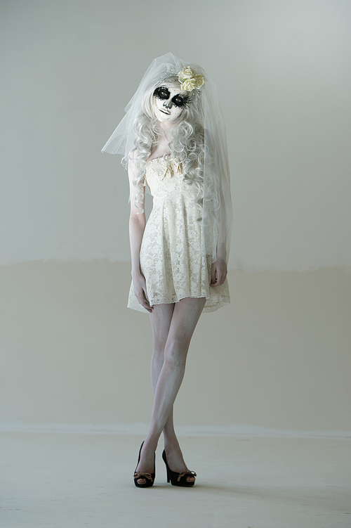 halloween witch. beautiful woman wearing 산타무에르테 mask and wedding dress posing full length
