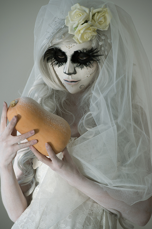 halloween witch. beautiful woman wearing 산타무에르테 mask holding pumpkin