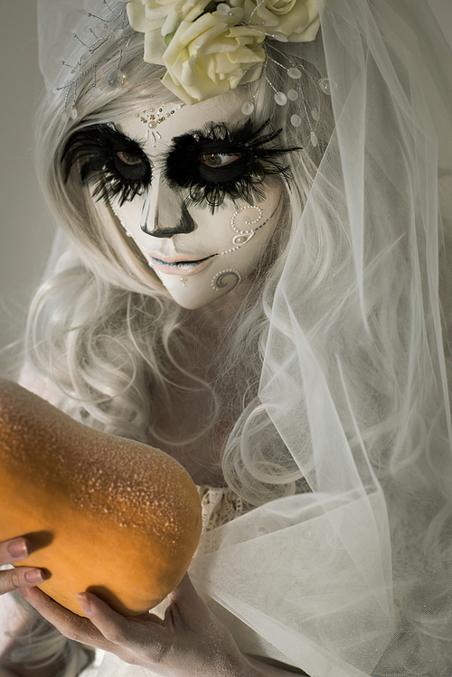 halloween witch. beautiful woman wearing s산타무에르테무에르테 mask holding pumpkin