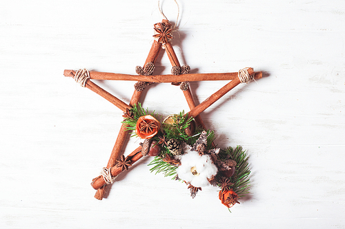 Christmas aromatic decor, cinnamon sticks tied as five-pointed star with rope, acorns and cotton flower