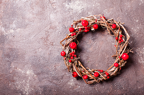 Woven wine wreath with red apples and berries over brown slate background. Holiday eco design