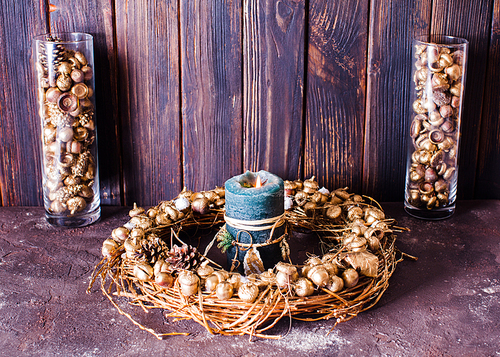 Golden acorns and pine cones in glasses and wreath, candlelight and decor for Christmas